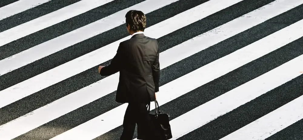 Homme en costume sur fond rayé noir et blanc.